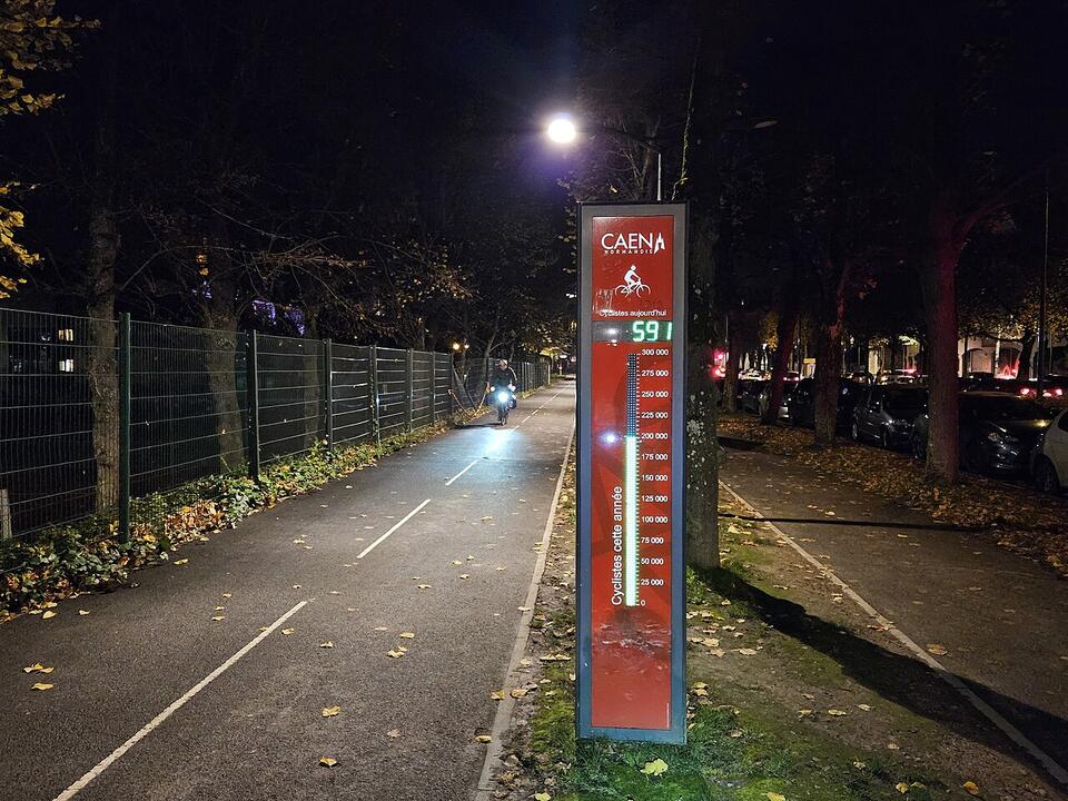 Totem compteur de vélos éclairé de nuit au bord d'une piste cyclable, à Caen